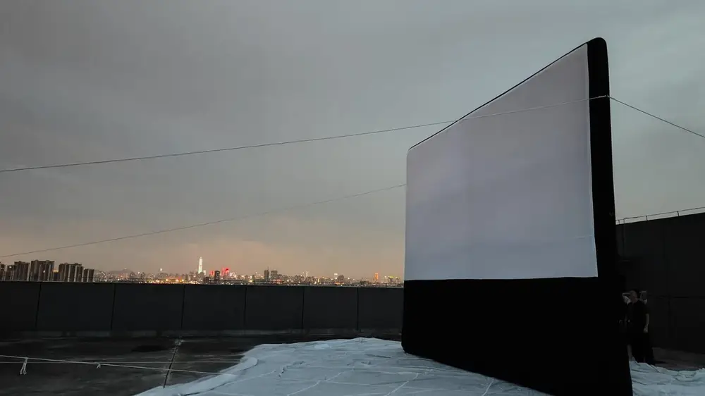 Projection nocturne sur écran gonflable installé sur un toit