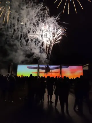 An evening show featuring three giant inflatable screens and fireworks in the background
