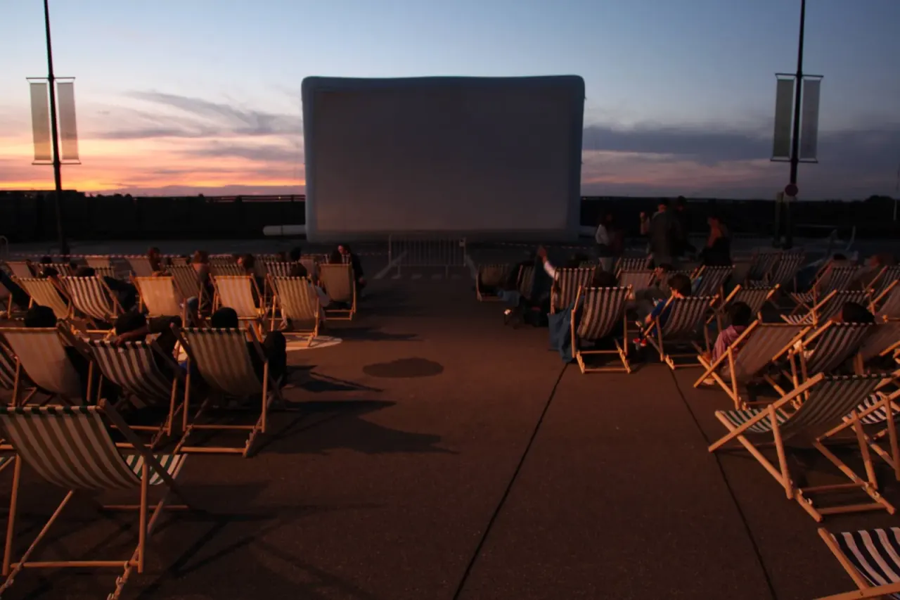 Turnkey outdoor movie screening: Hallucine inflatable screen, lounge chairs, and audience