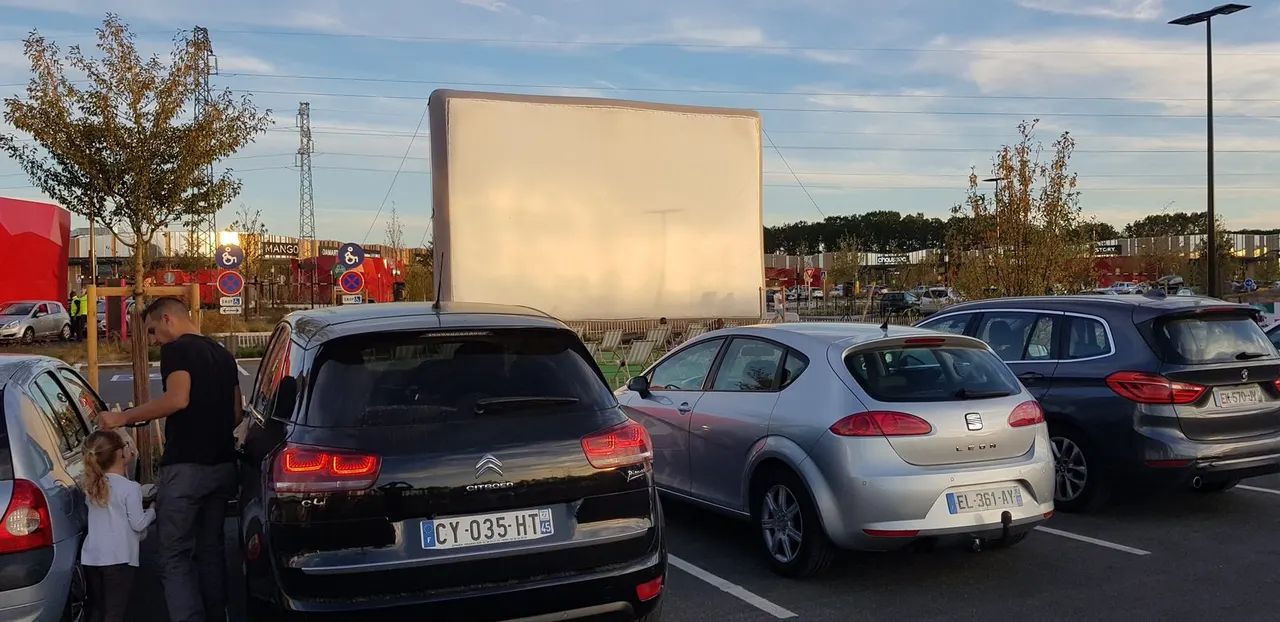 Pantalla de cine hinchable «Hallucine» instalada para una sesión de autocine, con los coches frente a la pantalla