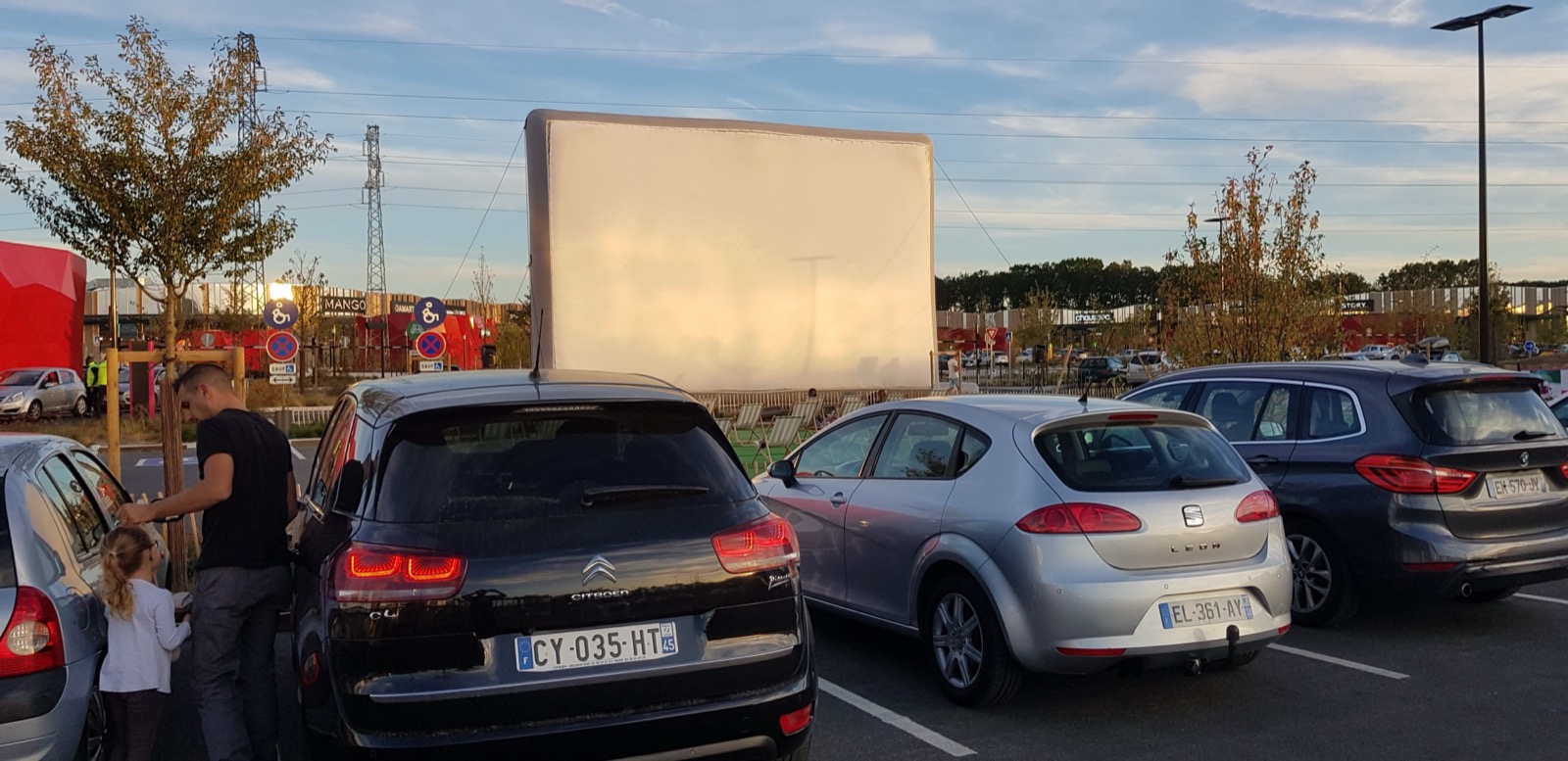 Écran de cinéma gonflable Hallucine installé pour une séance de drive-in, voitures face à la toile