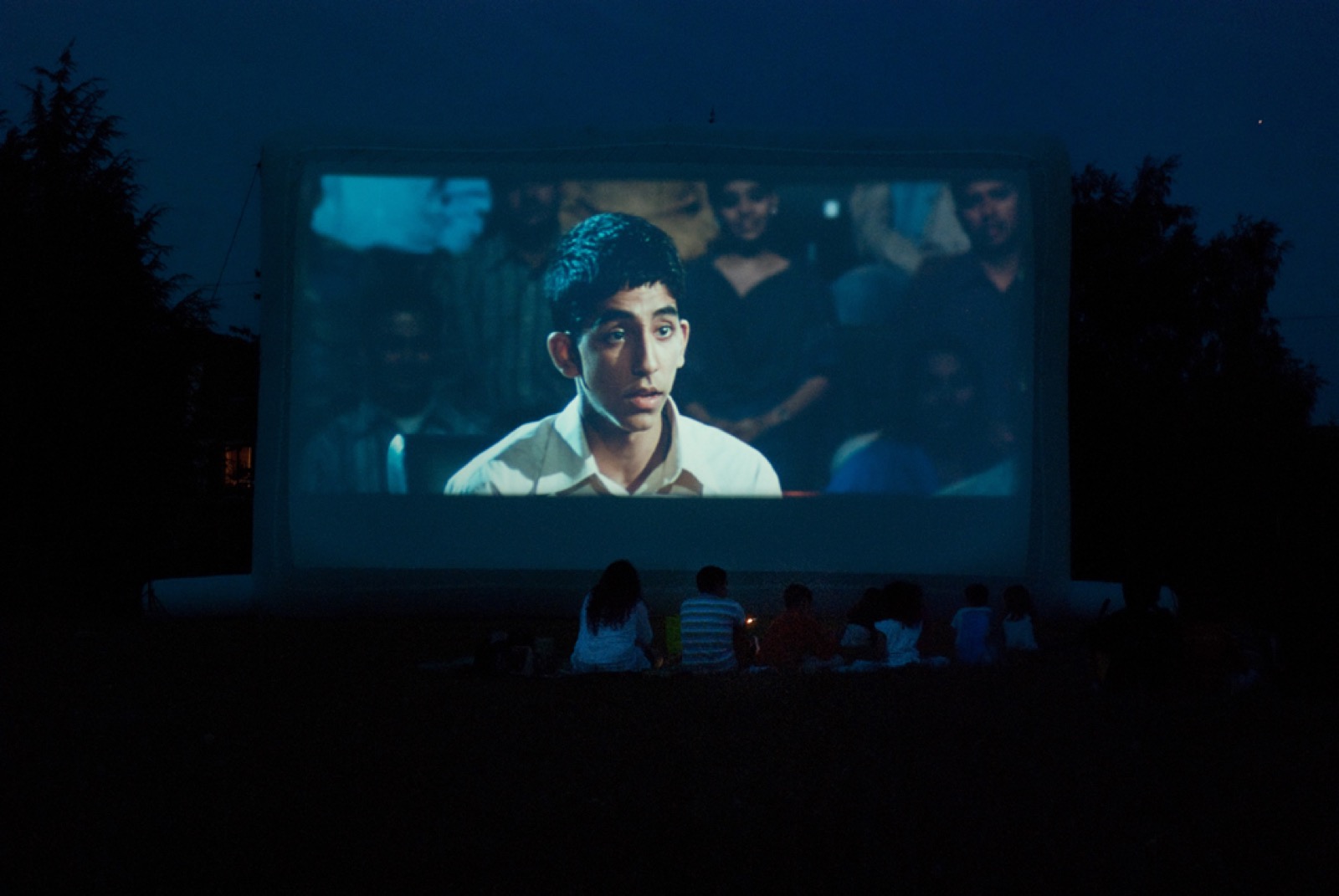 Séance de cinéma en plein air sur écran gonflable Hallucine à la nuit tombée, public installé devant la toile